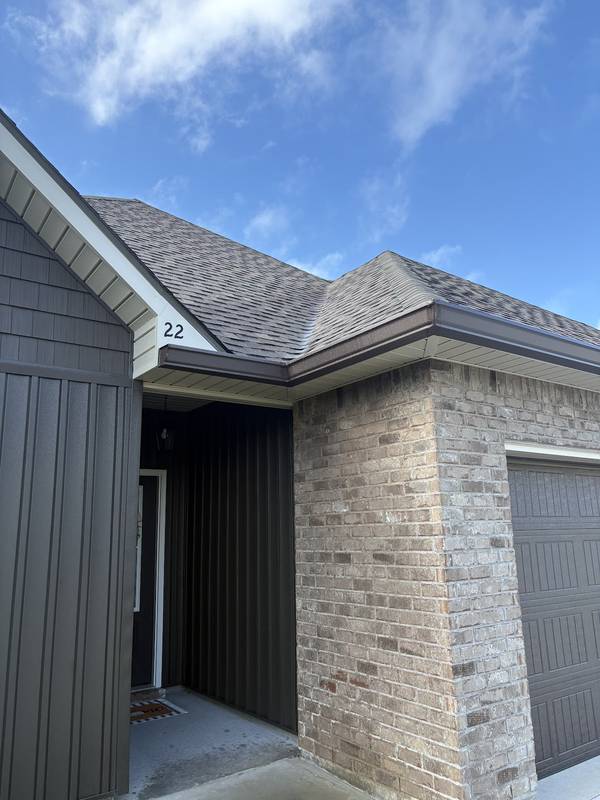 Dark bronze gutter along the roofline of a brick and board-and-batten home