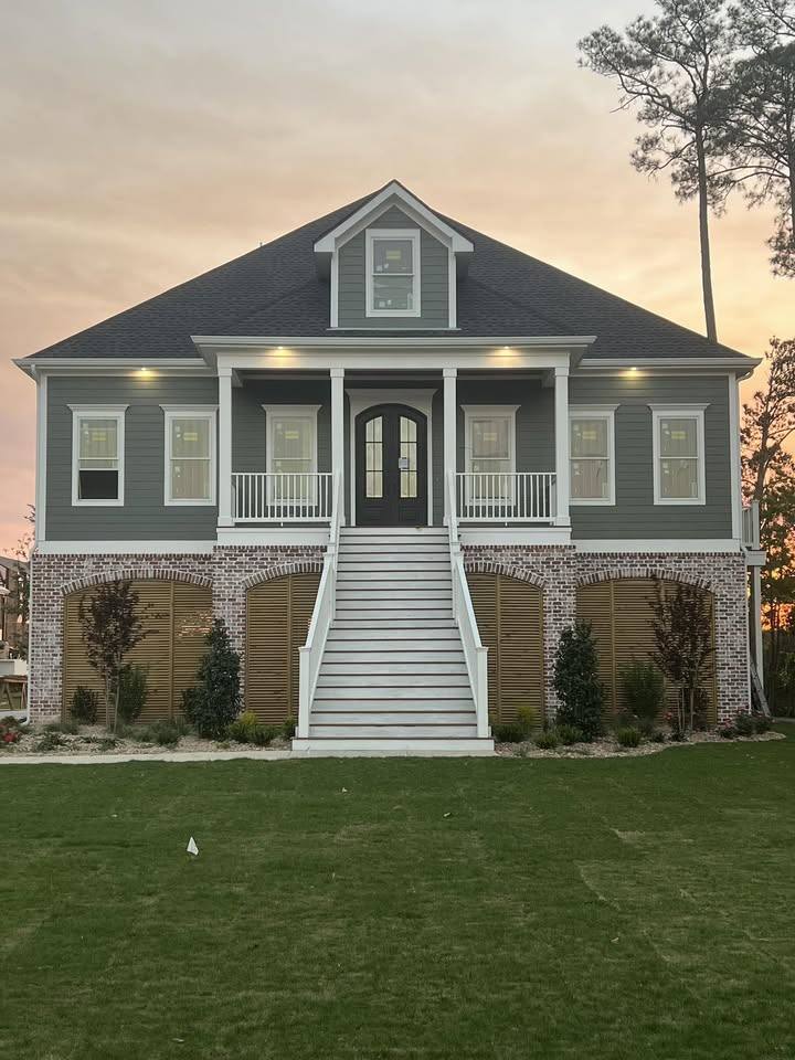 Raised gray-sided home with a brick base and a long front stair