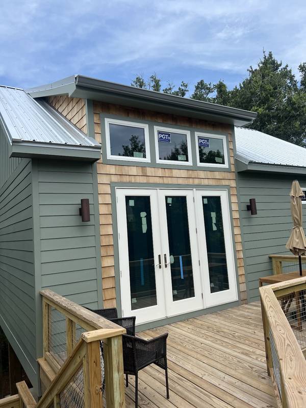 Gutters on a green and cedar-shingle coastal home above a wooden deck